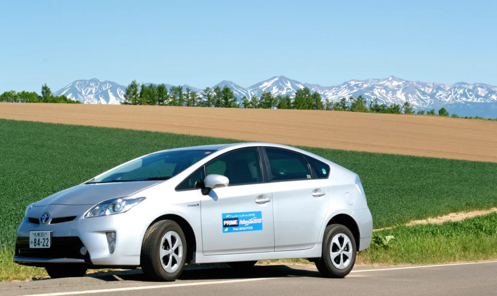 FMJ car next to fields backed by mountains